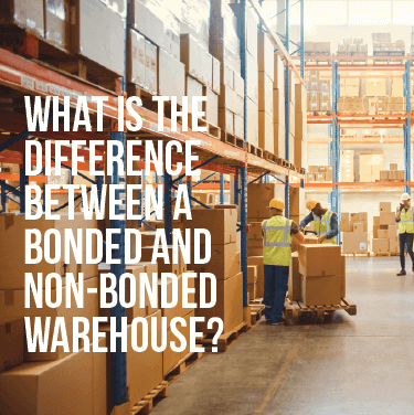 Two people packing boxes onto a pallet in a warehouse while another person in the background speaks on a phone