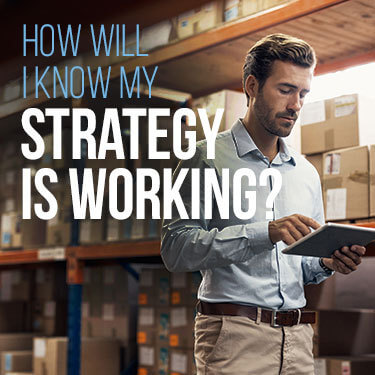 Man looking at a tablet while standing in a warehouse, boxes in the background