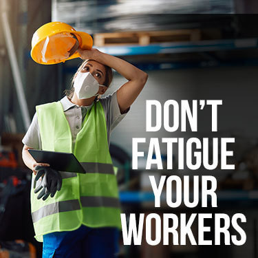 A warehouse worker taking their helmet off and wiping the sweat off their head