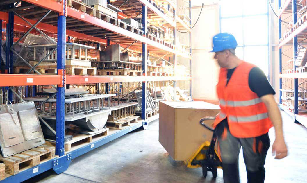 A warehouse worker moving products on a pallet jack.