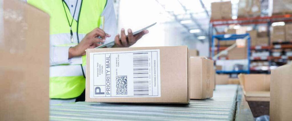 A warehouse worker with a tablet inspecting packed merchandise.